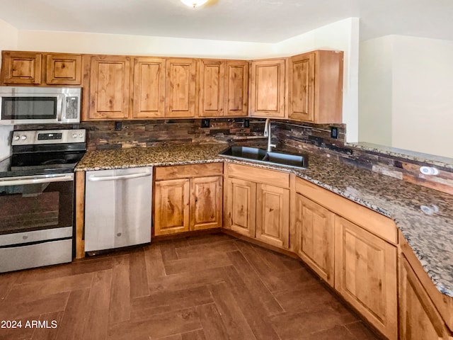 kitchen featuring appliances with stainless steel finishes, decorative backsplash, dark stone counters, and sink