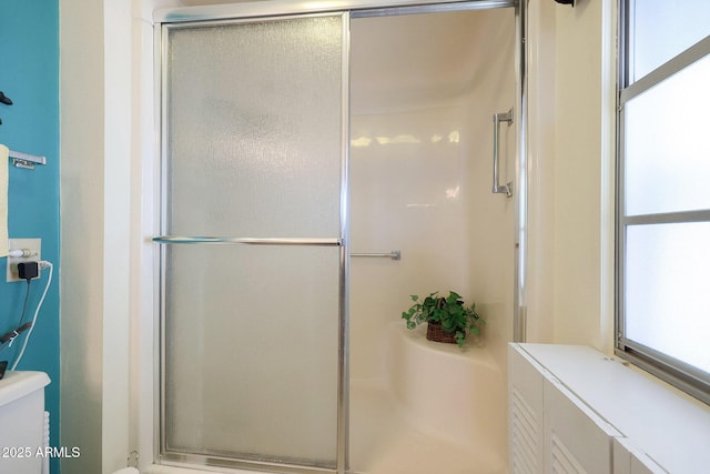 bathroom featuring a shower with shower door and toilet