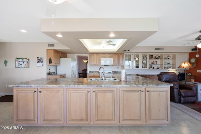 kitchen featuring ceiling fan, white appliances, light brown cabinetry, a large island with sink, and sink