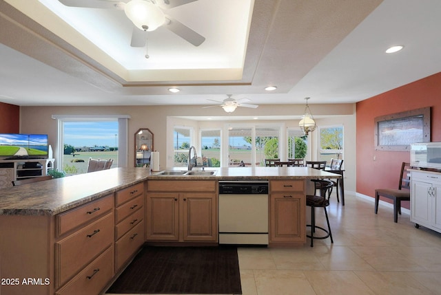 kitchen featuring pendant lighting, a raised ceiling, sink, white appliances, and a kitchen breakfast bar