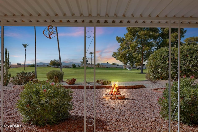 yard at dusk featuring an outdoor fire pit