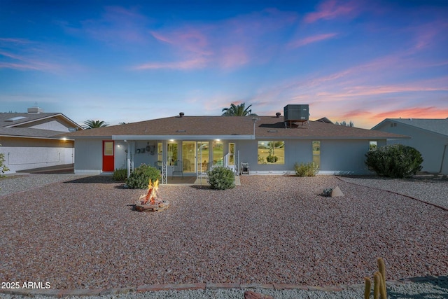 single story home with central AC unit, a fire pit, and a patio