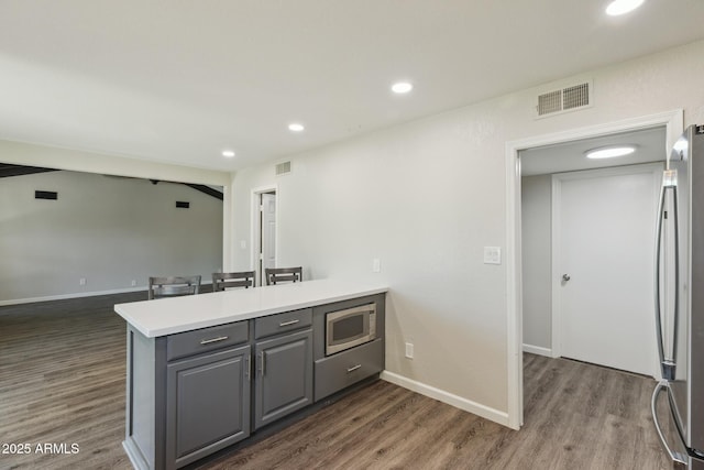 1452 E Gary St, Mesa, AZ 85203 - kitchen featuring appliances with stainless steel finishes, a peninsula, gray cabinets, dark wood-style flooring, and recessed lighting