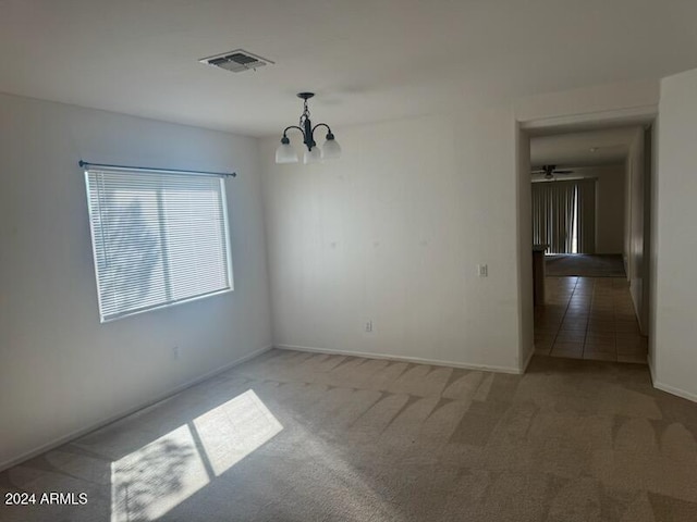 spare room with light colored carpet and ceiling fan with notable chandelier