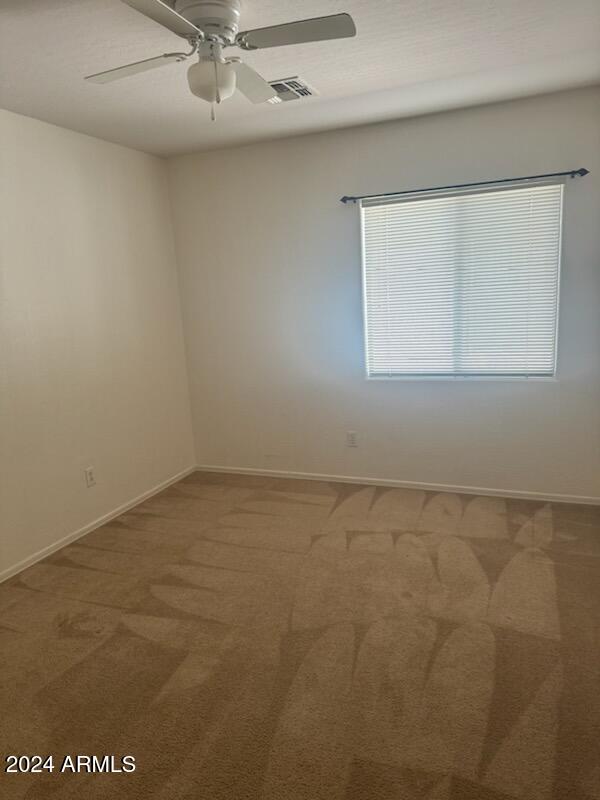 carpeted spare room featuring ceiling fan