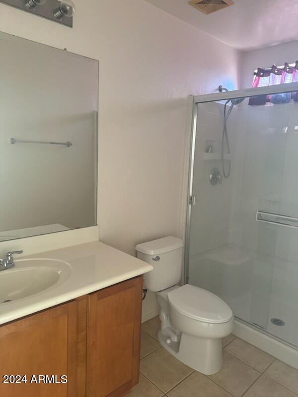 bathroom with walk in shower, tile patterned floors, vanity, and toilet