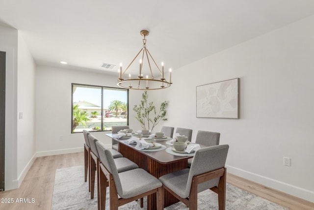 dining area featuring light wood-type flooring, baseboards, and a chandelier