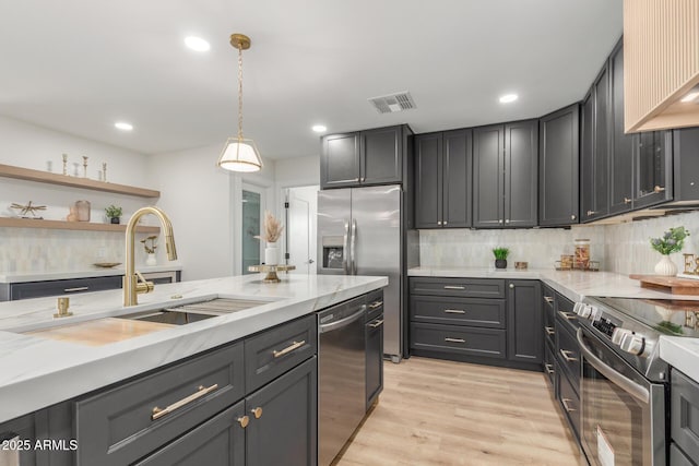 kitchen featuring a sink, decorative backsplash, appliances with stainless steel finishes, light stone countertops, and visible vents