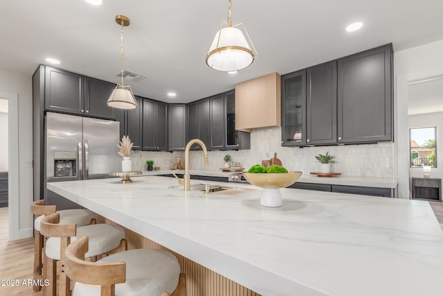 kitchen with visible vents, a sink, light stone counters, and tasteful backsplash