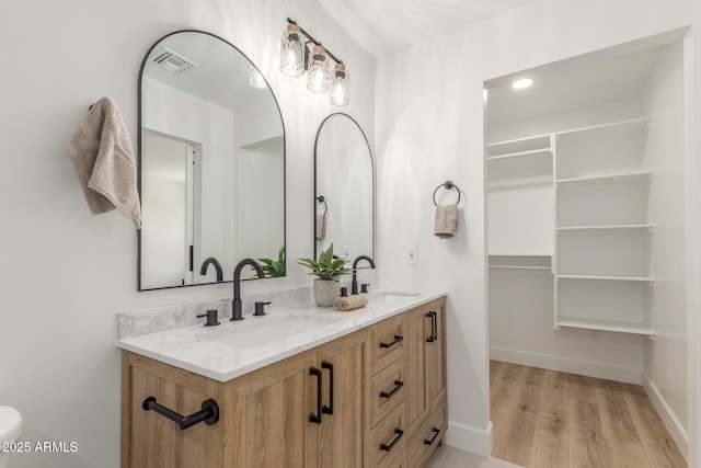 bathroom featuring double vanity, visible vents, wood finished floors, and a sink