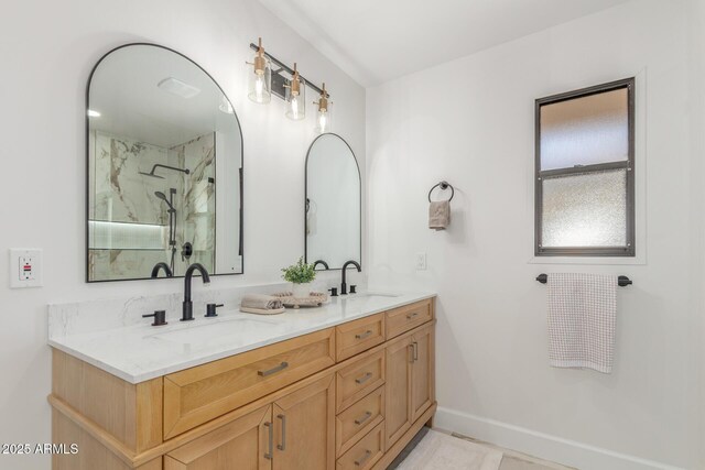 bathroom featuring double vanity, baseboards, a marble finish shower, and a sink