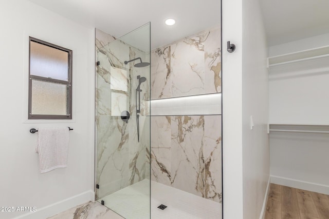 bathroom featuring baseboards, wood finished floors, a marble finish shower, and recessed lighting