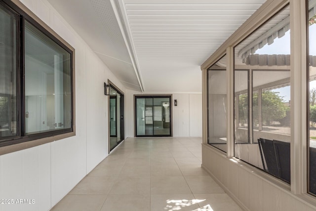 hallway with wood walls and light tile patterned floors
