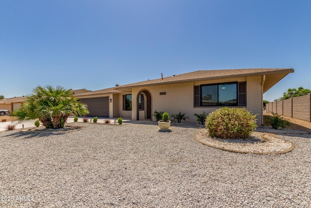single story home featuring brick siding, an attached garage, fence, and concrete driveway