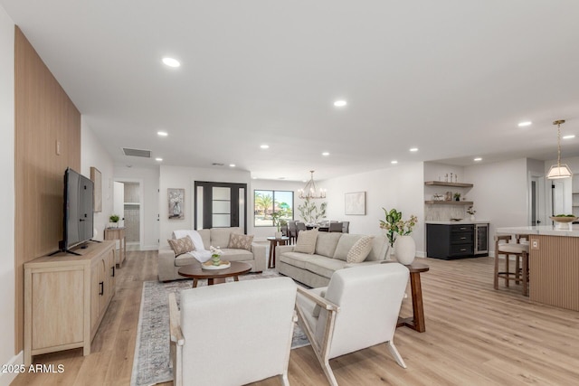 living room featuring light wood finished floors, visible vents, recessed lighting, and a notable chandelier