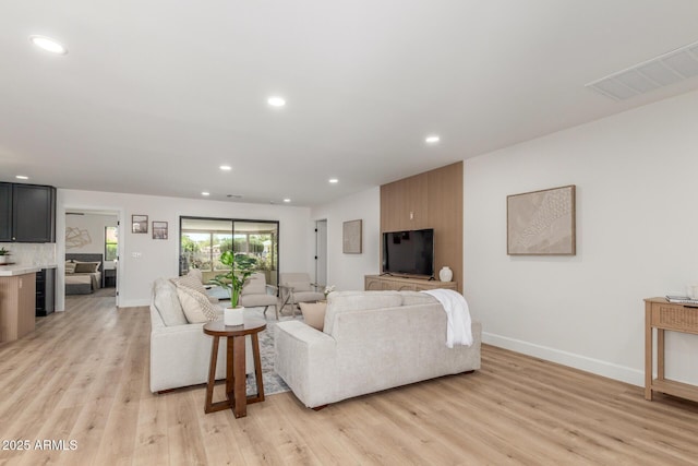living room with recessed lighting, visible vents, and light wood finished floors