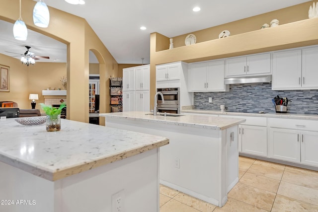 kitchen with sink, decorative light fixtures, white cabinetry, ceiling fan, and a kitchen island with sink