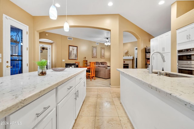 kitchen with pendant lighting, white cabinetry, double oven, ceiling fan, and sink