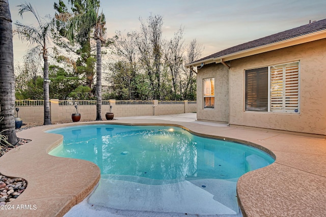 pool at dusk featuring a patio area