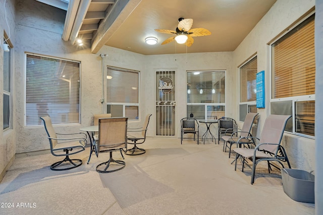 sunroom / solarium featuring ceiling fan and beam ceiling