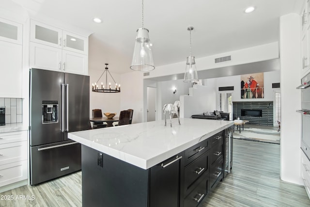 38953 N 57th Pl, Cave Creek, AZ 85331 - kitchen featuring high quality fridge, white cabinets, dark cabinetry, a glass covered fireplace, and a kitchen island