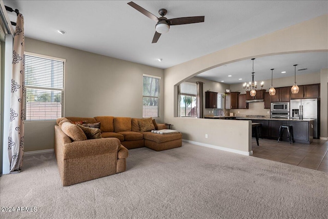 living room with plenty of natural light, ceiling fan with notable chandelier, and dark colored carpet