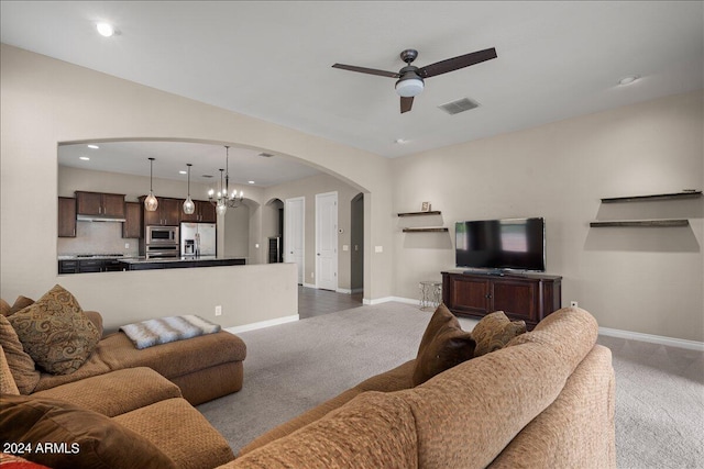 carpeted living room featuring ceiling fan with notable chandelier