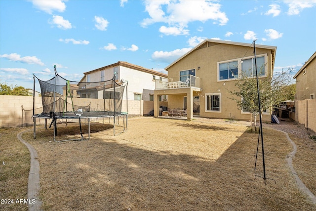 rear view of house with a balcony and a trampoline