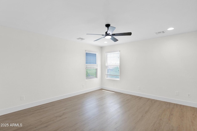 empty room with wood finished floors, visible vents, and a ceiling fan
