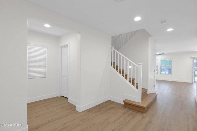 stairs with baseboards, wood finished floors, and recessed lighting