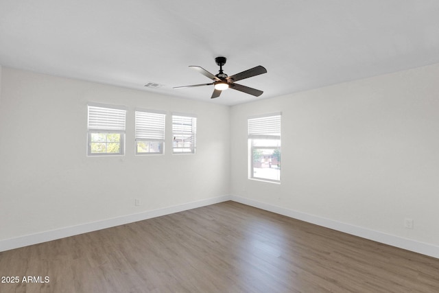 spare room with wood finished floors, a wealth of natural light, and ceiling fan