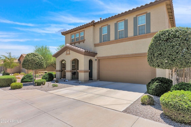 mediterranean / spanish house featuring stucco siding, concrete driveway, a tiled roof, and a garage
