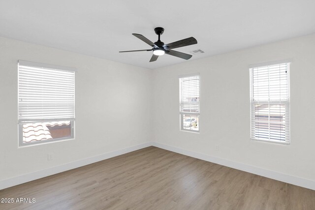 unfurnished room with baseboards, wood finished floors, visible vents, and ceiling fan