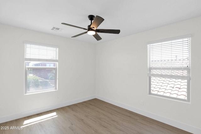 empty room with ceiling fan, baseboards, wood finished floors, and visible vents