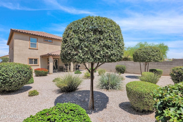 exterior space featuring stucco siding, fence, and a tiled roof