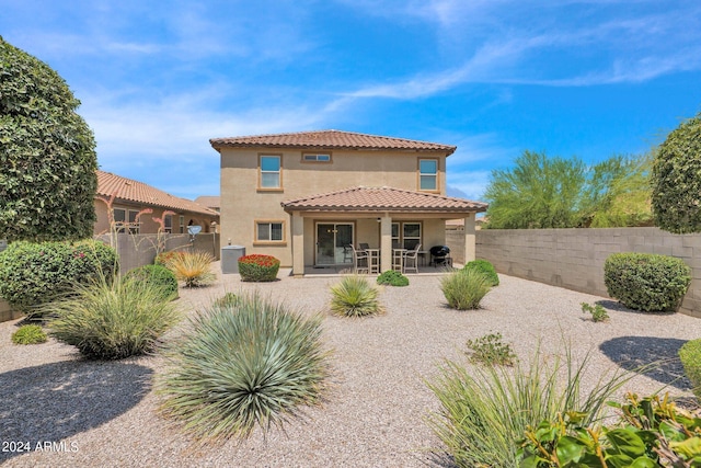 rear view of house featuring central AC unit, a patio area, a tiled roof, a fenced backyard, and stucco siding