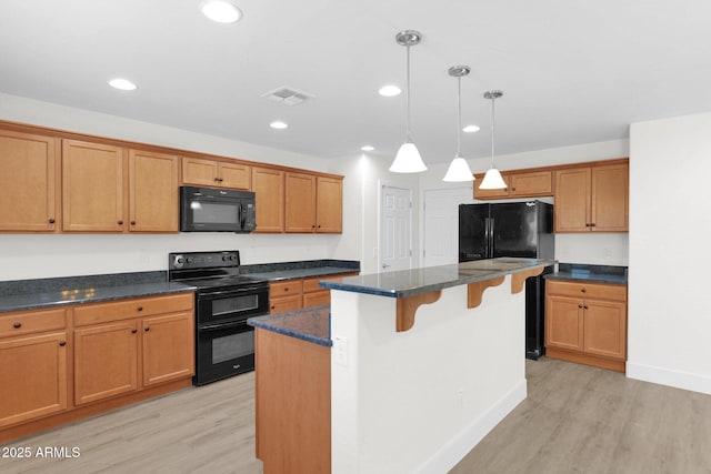 kitchen with a kitchen bar, light wood-type flooring, visible vents, and black appliances