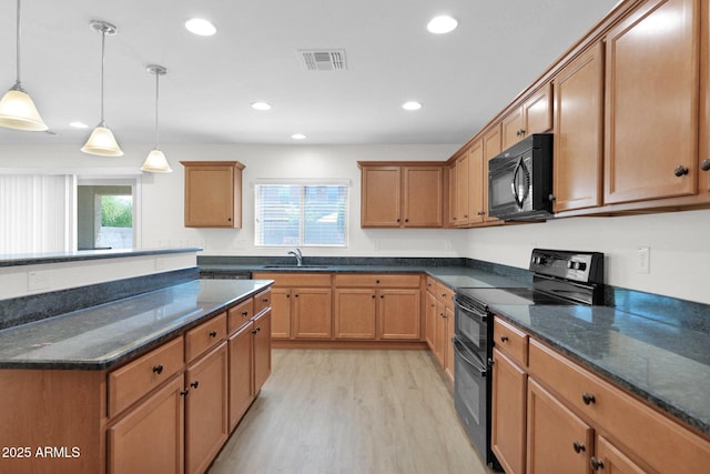 kitchen featuring visible vents, a sink, light wood-style floors, decorative light fixtures, and black appliances