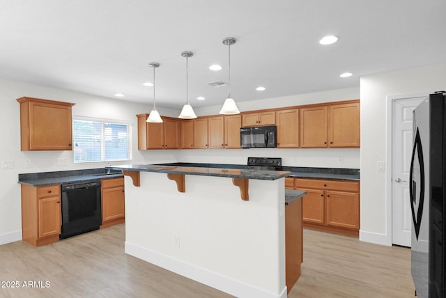 kitchen with light wood-type flooring, visible vents, recessed lighting, a breakfast bar, and black appliances