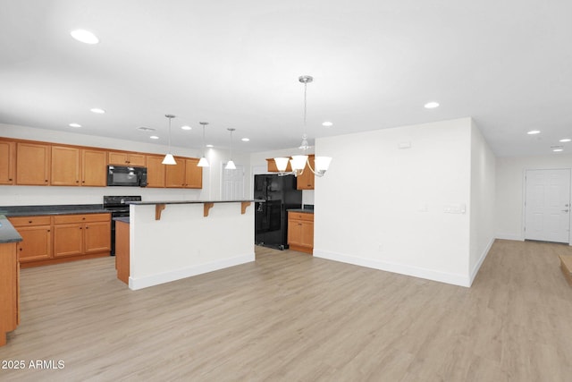 kitchen featuring black appliances, a kitchen breakfast bar, light wood finished floors, and recessed lighting