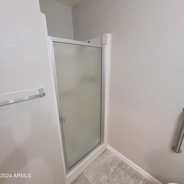 bathroom with a shower with door and tile patterned flooring