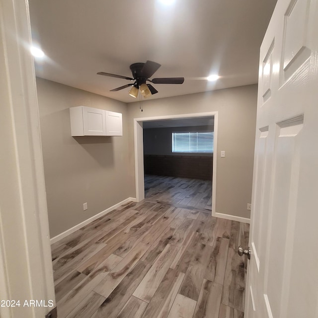 empty room with ceiling fan and light hardwood / wood-style flooring