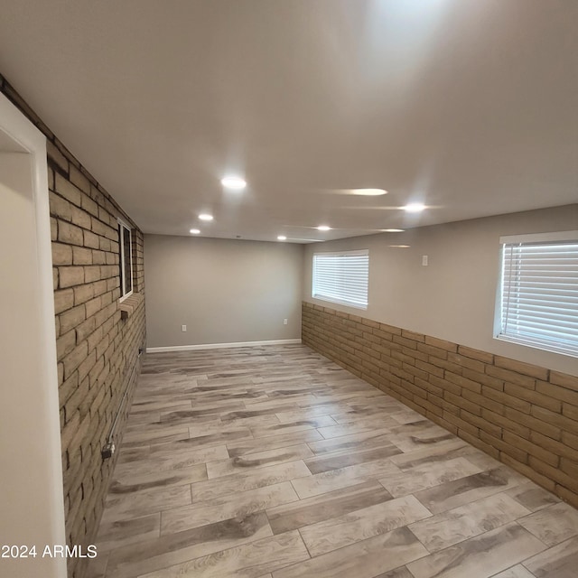 basement featuring brick wall and light wood-type flooring