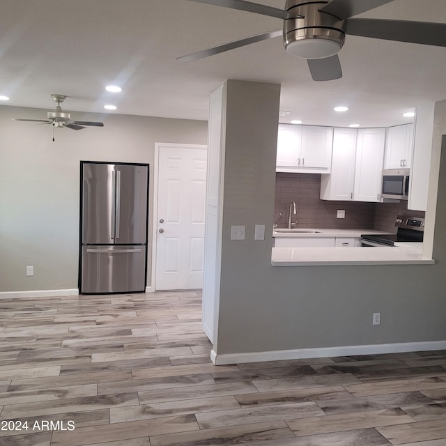 kitchen with ceiling fan, appliances with stainless steel finishes, sink, backsplash, and white cabinetry