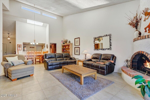 tiled living room featuring a brick fireplace, a high ceiling, a textured ceiling, and a notable chandelier