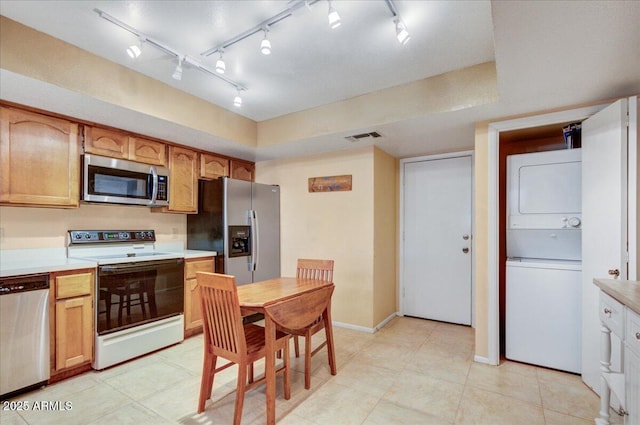 kitchen with stacked washer / drying machine and appliances with stainless steel finishes