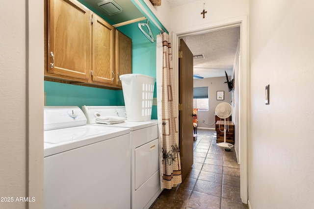 washroom with cabinets, a textured ceiling, and washing machine and clothes dryer