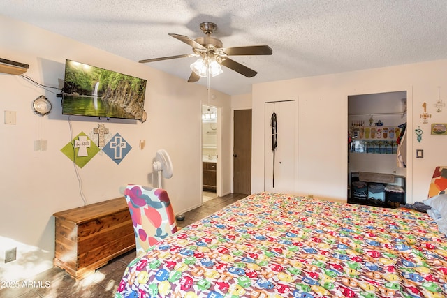 tiled bedroom featuring ceiling fan, multiple closets, a textured ceiling, and ensuite bath