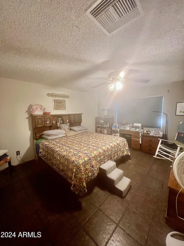 tiled bedroom with ceiling fan and a textured ceiling