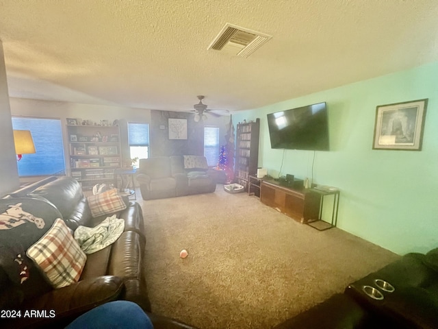 living room with carpet, ceiling fan, and a textured ceiling